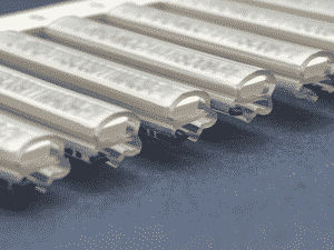 Close-up of several translucent Slide-On Sleeves lined up in a row on a dark textured surface, showing details of their curved and interlocking edges.