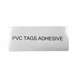 A 100mm x 60mm metallic/grey adhesive PVC tag, labeled "PVC TAGS ADHESIVE" in bold black, perfect for panels and equipment.