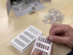 Close up of a person's hands as they insert sleeves over wire marking tags on a backbone.